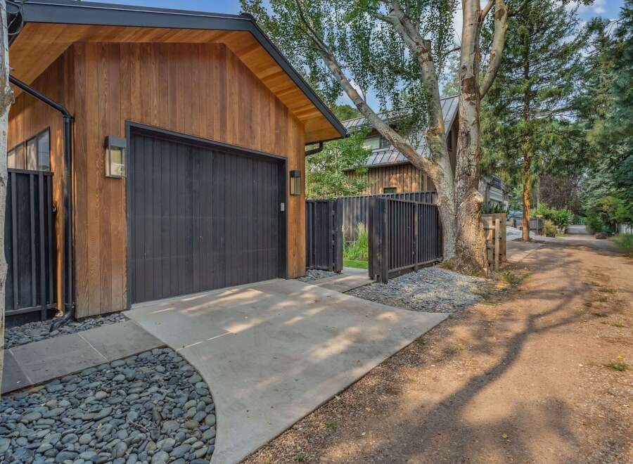 Discover modern living with this stunning property featuring a sleek wooden exterior and a striking black garage door.