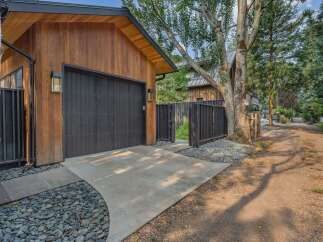 Discover modern living with this stunning property featuring a sleek wooden exterior and a striking black garage door.