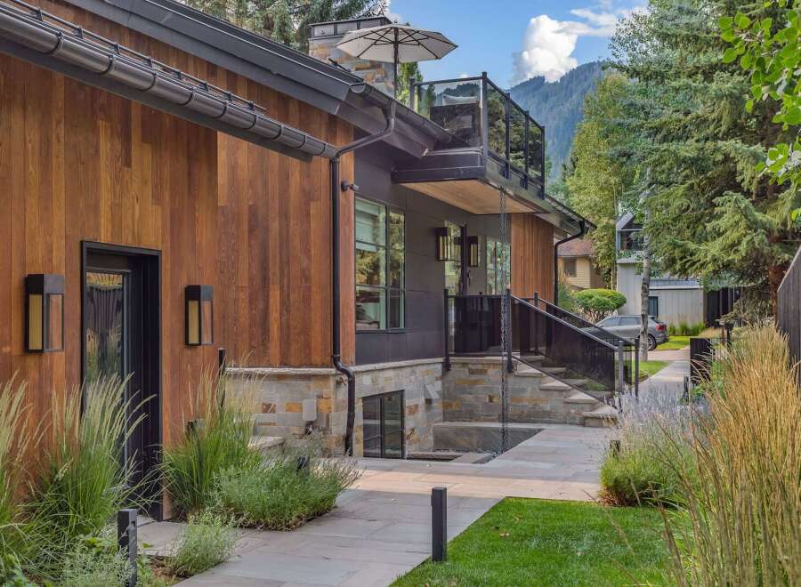 Experience modern luxury in this stunning home featuring a striking combination of warm wood siding and sleek dark metal accents.