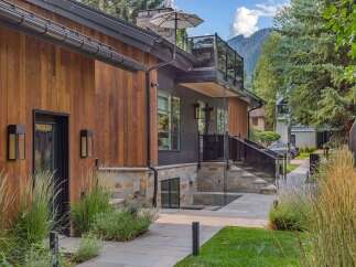 Experience modern luxury in this stunning home featuring a striking combination of warm wood siding and sleek dark metal accents.