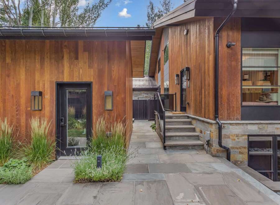 Experience modern luxury in this stunning home featuring warm wood siding and natural stone accents.