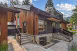Experience modern luxury in this stunning home featuring a striking blend of natural wood and dark metal siding.