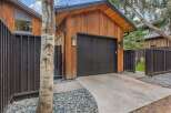 This modern garage features a striking vertical wood-paneled exterior complemented by a sleek black garage door and matching fence.