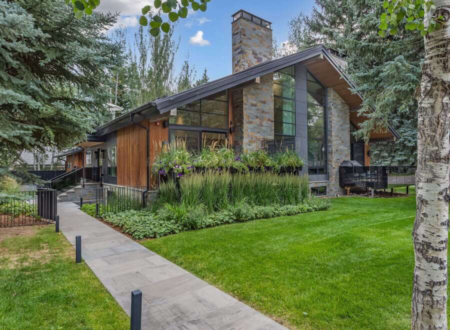 Experience modern luxury in this stunning home featuring a striking stone chimney and expansive windows that invite natural light.