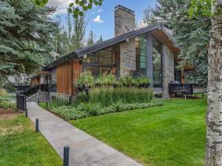 Experience modern luxury in this stunning home featuring a striking stone chimney and expansive windows that invite natural light.