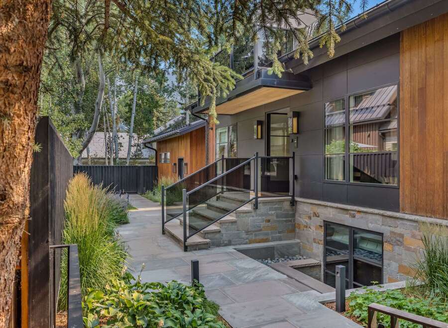 Experience modern luxury in this stunning home featuring a sleek dark exterior with warm wood accents.