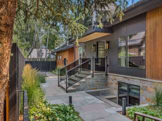 Experience modern luxury in this stunning home featuring a sleek dark exterior with warm wood accents.