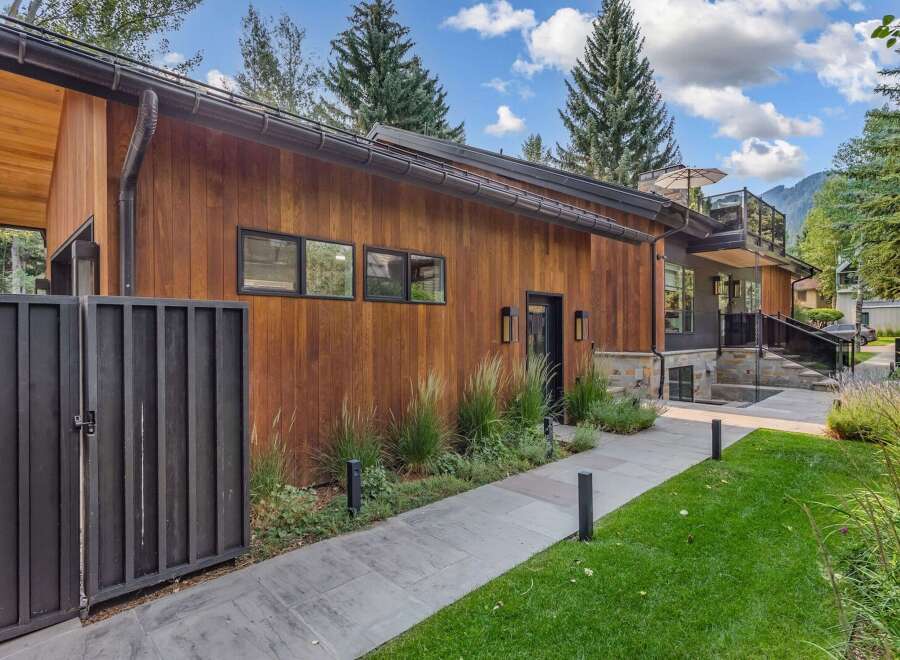 Experience modern luxury in this stunning home featuring warm wood siding and sleek black accents.