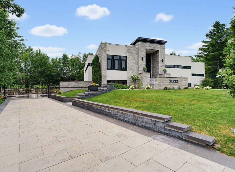 Experience luxury living in this stunning modern residence, featuring a striking stone facade and expansive manicured grounds.