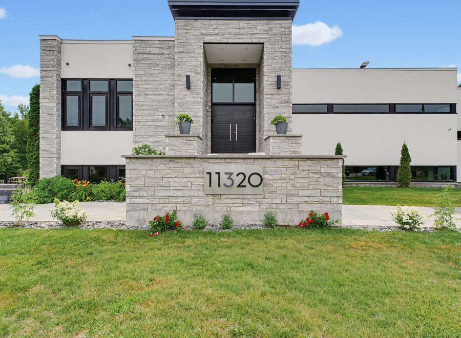 Experience modern luxury in this stunning residence featuring a striking stone facade and expansive windows.