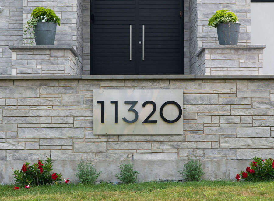 Modern elegance meets natural beauty at this stunning property, featuring a sleek facade with a contemporary double door entrance.