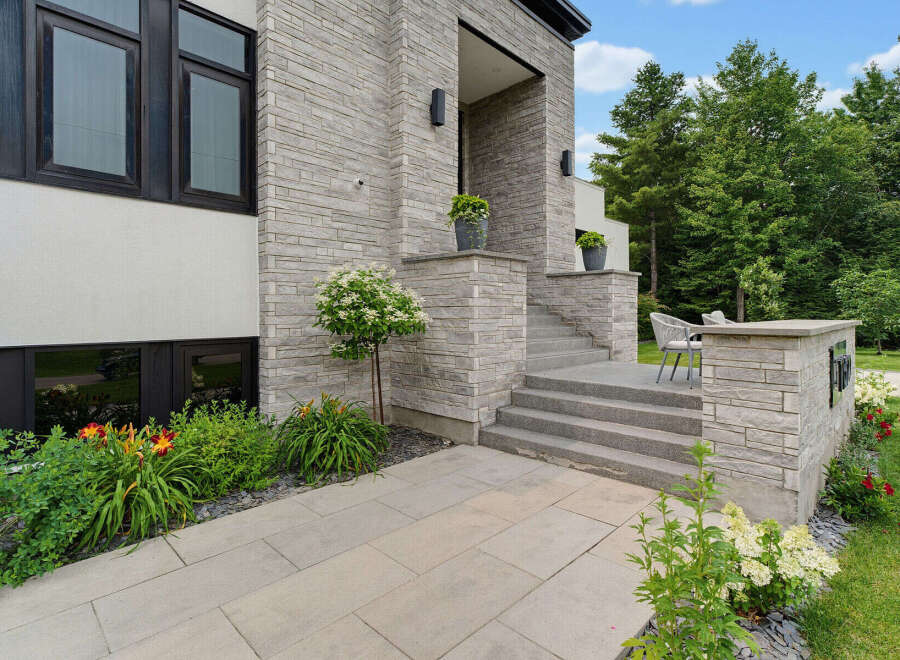 This modern home features a striking facade with a combination of light grey stacked stone and white stucco.