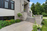 This modern home features a striking facade with a combination of light grey stacked stone and white stucco.