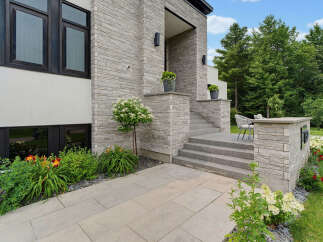 This modern home features a striking facade with a combination of light grey stacked stone and white stucco.