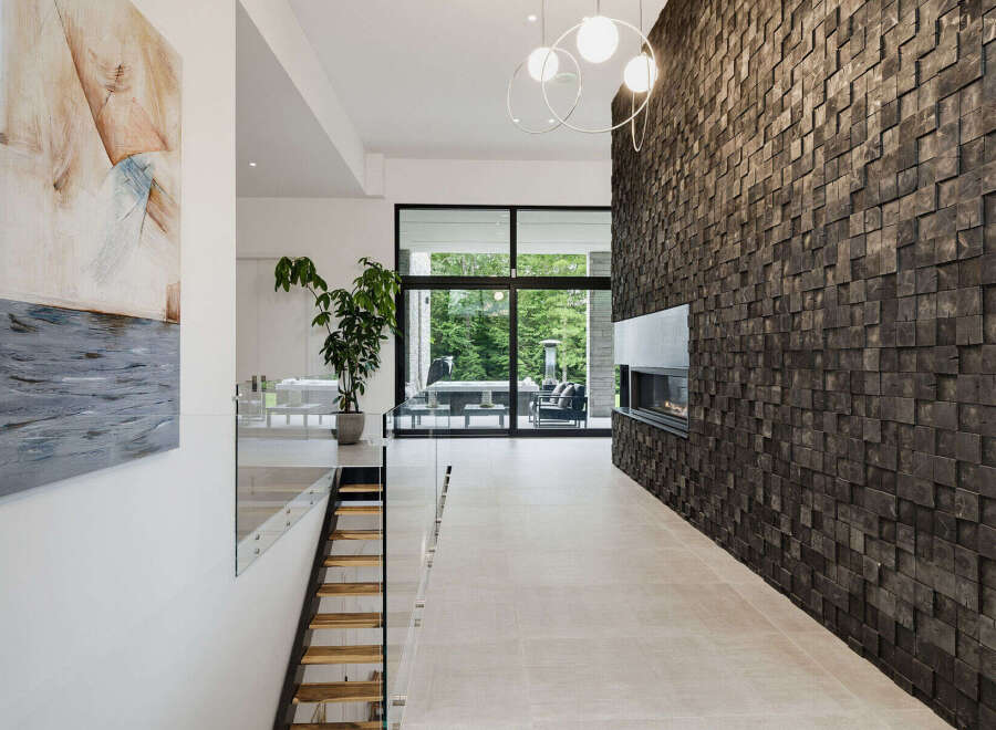 Experience modern luxury in this stunning entryway featuring a dramatic wood-paneled accent wall with a sleek fireplace.