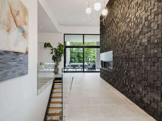 Experience modern luxury in this stunning entryway featuring a dramatic wood-paneled accent wall with a sleek fireplace.