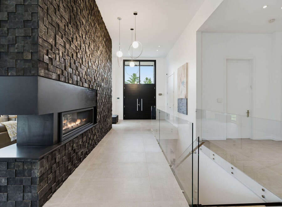 Experience modern luxury in this stunning entryway featuring a dramatic floor-to-ceiling wood-paneled wall with a sleek linear fireplace.