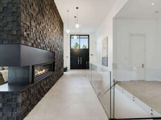 Experience modern luxury in this stunning entryway featuring a dramatic floor-to-ceiling wood-paneled wall with a sleek linear fireplace.