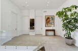 This spacious hallway features a modern design with sleek glass railings and neutral-toned tiled flooring.