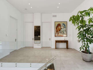 This spacious hallway features a modern design with sleek glass railings and neutral-toned tiled flooring.