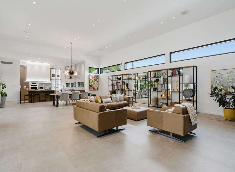 Experience luxurious open-concept living in this stunning modern home, featuring a spacious living area with plush leather seating and a sleek dining space adjacent to a gourmet kitchen.