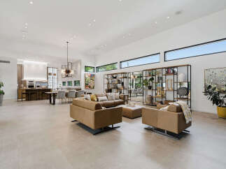 Experience luxurious open-concept living in this stunning modern home, featuring a spacious living area with plush leather seating and a sleek dining space adjacent to a gourmet kitchen.