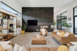 Experience modern luxury in this spacious living room, featuring a striking black stone accent wall with a sleek fireplace and integrated television.