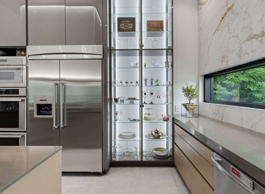 Experience luxury living in this modern kitchen, featuring sleek stainless steel appliances including a side-by-side refrigerator and built-in ovens.