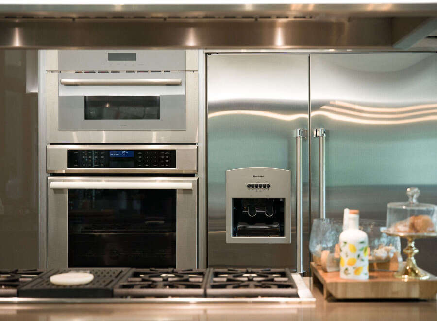 Experience luxury in this modern kitchen, featuring a sleek stainless steel refrigerator and a built-in oven and microwave combination.