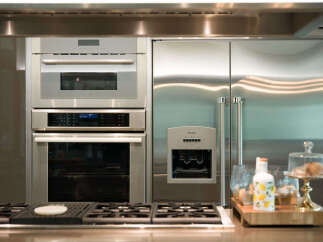Experience luxury in this modern kitchen, featuring a sleek stainless steel refrigerator and a built-in oven and microwave combination.