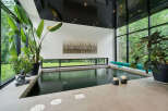 Experience ultimate relaxation in this indoor oasis, featuring a sleek, dark-water pool surrounded by lush greenery and expansive windows.