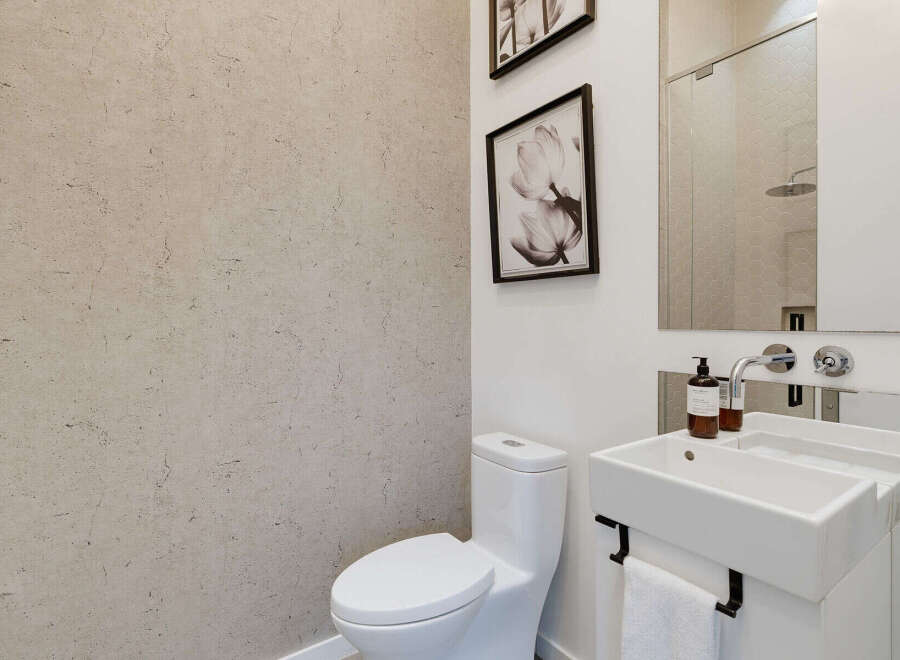 This modern bathroom features a sleek white toilet and a minimalist vanity with a unique integrated sink.