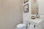 This modern bathroom features a sleek white toilet and a minimalist vanity with a unique integrated sink.