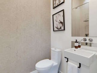 This modern bathroom features a sleek white toilet and a minimalist vanity with a unique integrated sink.