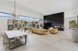 Experience modern luxury in this expansive open-concept living and dining area, featuring a striking black stone fireplace and a unique sputnik chandelier.