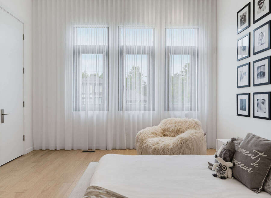 This bright and airy bedroom features sheer white curtains that allow natural light to flood the space, creating a serene atmosphere.