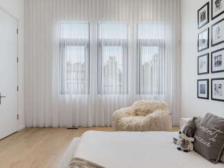 This bright and airy bedroom features sheer white curtains that allow natural light to flood the space, creating a serene atmosphere.