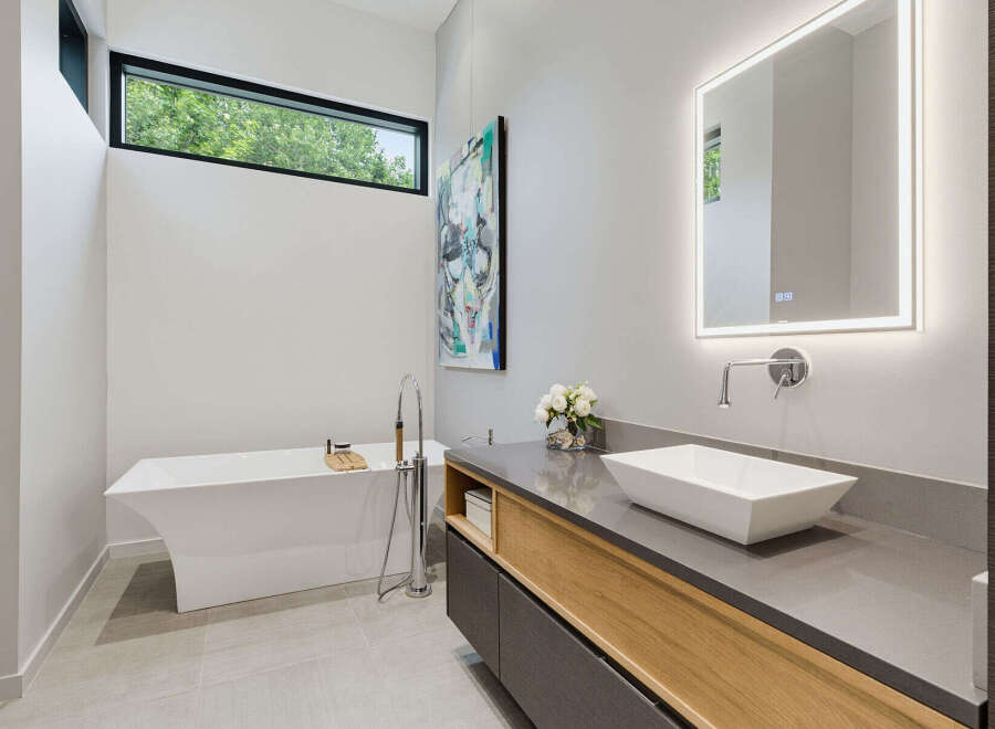 Experience modern luxury in this stunning bathroom, featuring a sleek freestanding bathtub and a floating vanity with a vessel sink.