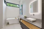 Experience modern luxury in this stunning bathroom, featuring a sleek freestanding bathtub and a floating vanity with a vessel sink.