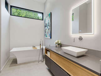 Experience modern luxury in this stunning bathroom, featuring a sleek freestanding bathtub and a floating vanity with a vessel sink.