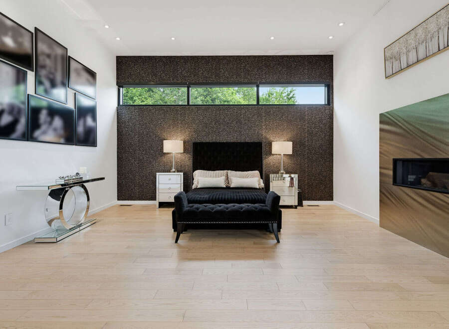 Experience modern luxury in this master bedroom featuring a striking tufted headboard and plush seating.
