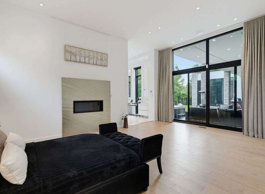 Experience modern luxury in this spacious living area, featuring a sleek fireplace and expansive floor-to-ceiling windows that flood the room with natural light.
