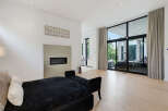 Experience modern luxury in this spacious living area, featuring a sleek fireplace and expansive floor-to-ceiling windows that flood the room with natural light.