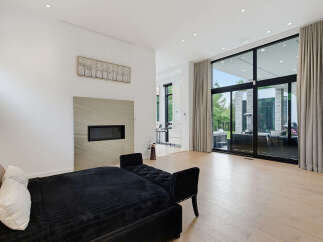 Experience modern luxury in this spacious living area, featuring a sleek fireplace and expansive floor-to-ceiling windows that flood the room with natural light.