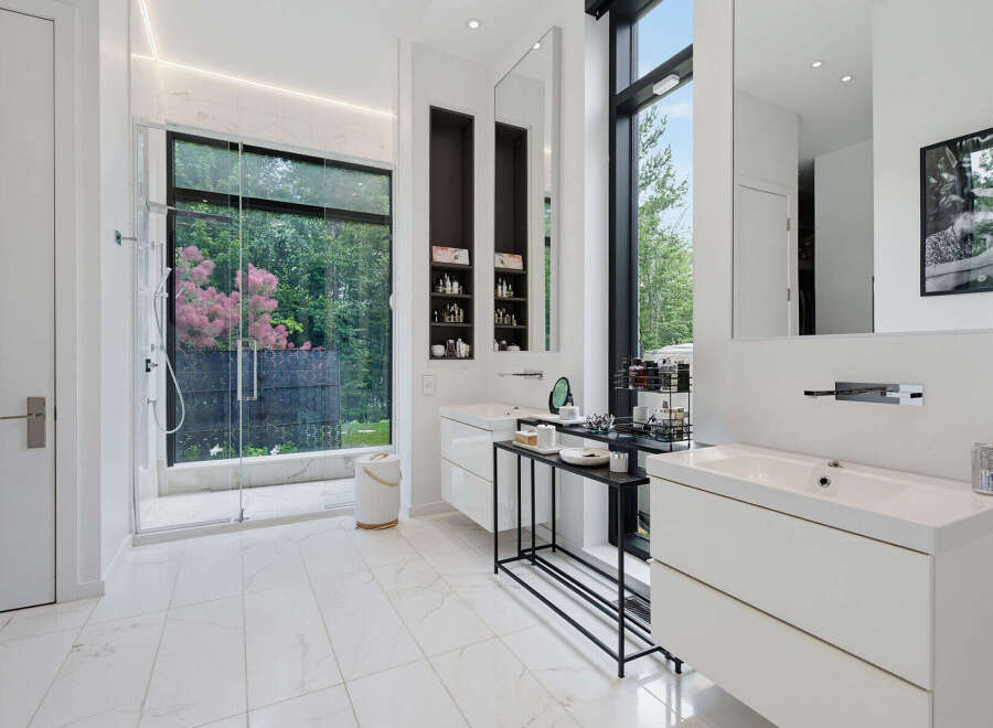 Experience luxury in this modern bathroom featuring a spacious walk-in shower with a scenic garden view.