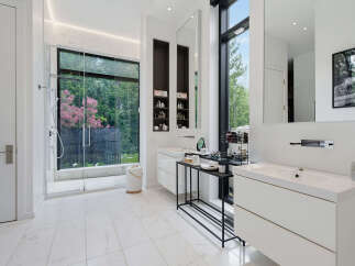 Experience luxury in this modern bathroom featuring a spacious walk-in shower with a scenic garden view.