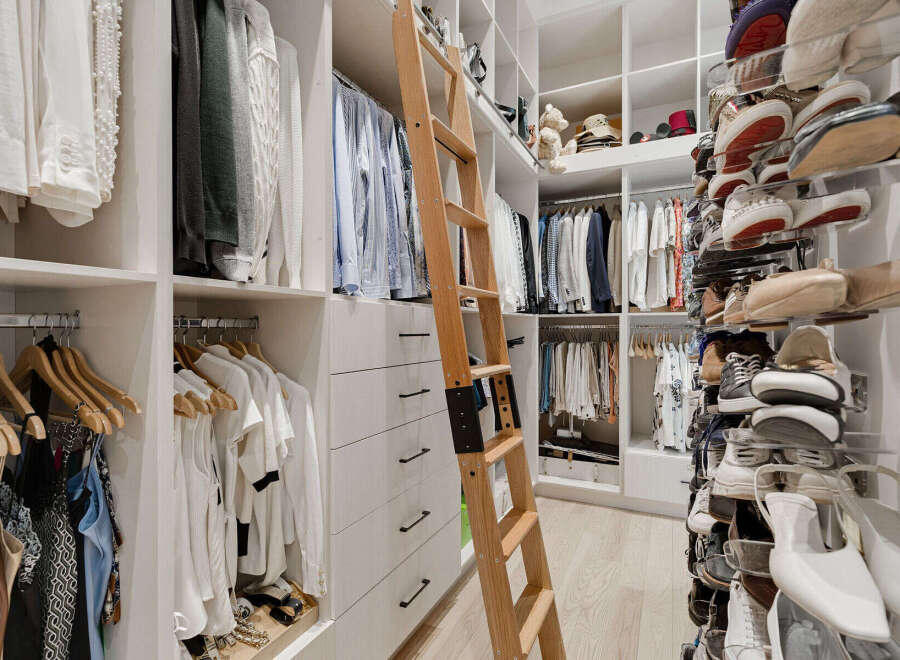 Experience unparalleled organization in this luxurious walk-in closet, featuring a custom ladder for easy access to upper shelves.
