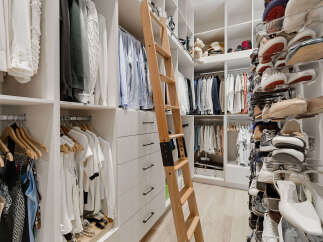 Experience unparalleled organization in this luxurious walk-in closet, featuring a custom ladder for easy access to upper shelves.
