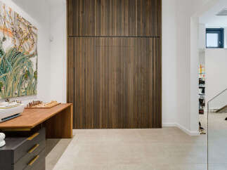 This modern home office features a striking slatted wood accent wall, creating a warm and inviting atmosphere.