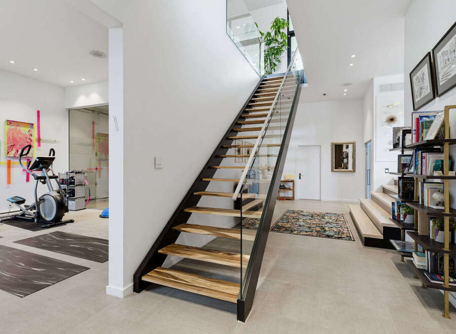 Discover a modern and spacious home featuring a dedicated home gym area with cardio equipment and yoga mats.